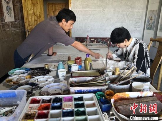 圖為2020年8月下旬，敦煌“80后”畫家張杰龍(左)在為云南麗江“學生”莫北講解敦煌壁畫的繪畫技巧?！●T志軍 攝