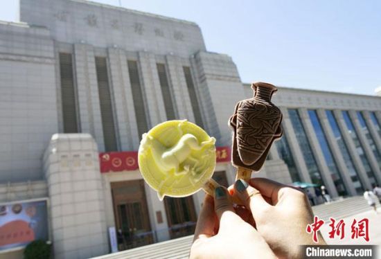 2021年7月30日，游客手拿“銅奔馬”“彩陶瓶”造型的雪糕，在甘肅省博物館前拍照打卡?！「哒?攝