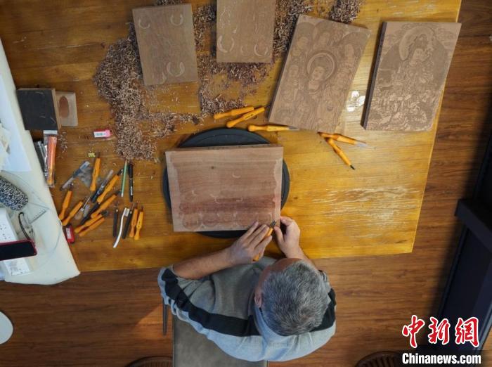圖為徐晉林正在梨木木板上雕刻敦煌壁畫(huà)?！【琶赖┰?　攝