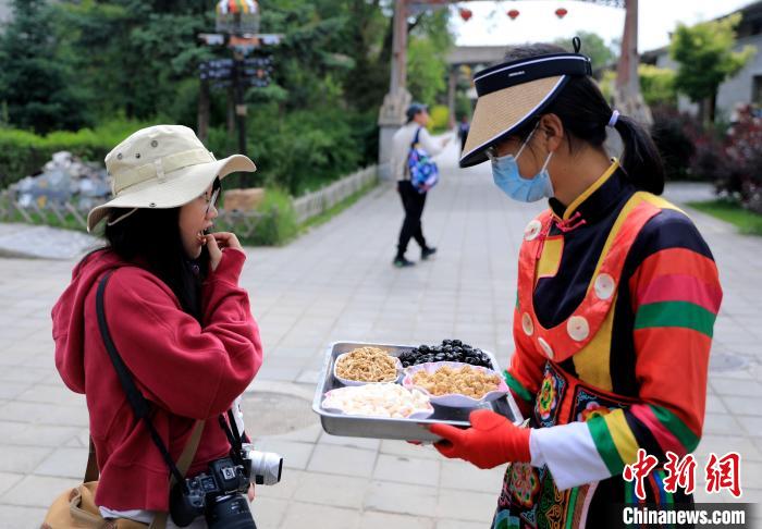 圖為身穿土族服飾的女性介紹當(dāng)?shù)靥厣〕浴！⊙Φ?攝