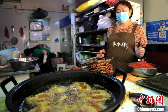 圖為平安驛·河湟民俗文化體驗(yàn)地內(nèi)的商戶炸干板魚?！⊙Φ?攝