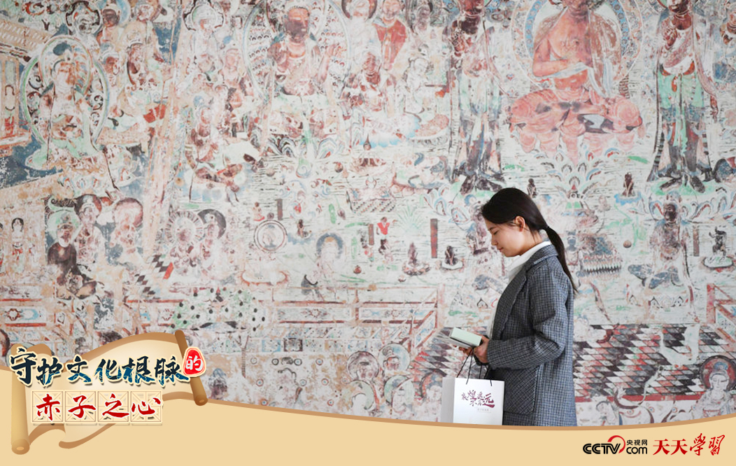 2023年4月25日，敦煌研究院文物數(shù)字化保護(hù)團(tuán)隊(duì)創(chuàng)意營銷人員廖雪婷從一幅高保真復(fù)制壁畫前走過。