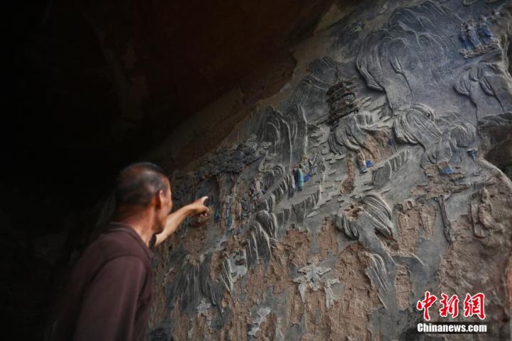 7月15日，甘肅省平?jīng)鍪袥艽h百里石窟長廊羅漢洞石窟內(nèi)，該窟文保員郭建平介紹窟內(nèi)石刻彩繪壁畫。郭建平家中三代人曾自發(fā)保護羅漢洞石窟。羅漢洞石窟遺存40余個窟龕，以北魏至清代風(fēng)格為主。中新社記者 李亞龍 攝