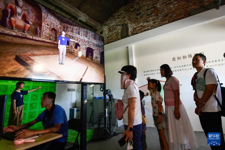 7月22日，游客體驗“尋境敦煌——數(shù)字敦煌沉浸展”后，在虛擬演播廳拍攝一段真人與洞窟虛擬場景交互的視頻。新華社記者 郎兵兵 攝</p>
<p>