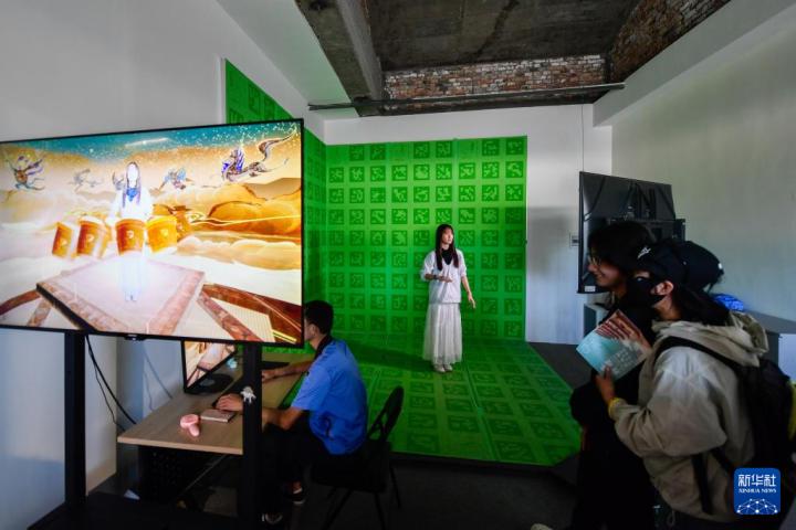 7月22日，游客體驗“尋境敦煌——數(shù)字敦煌沉浸展”后，在虛擬演播廳拍攝一段真人與洞窟虛擬場景交互的視頻。新華社記者 郎兵兵 攝</p>
<p>